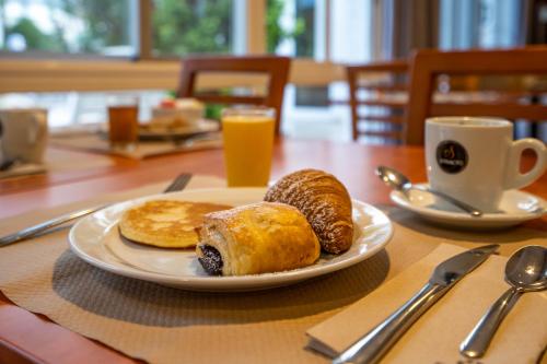 a table with a plate of breakfast foods and a cup of orange juice at Hotel Bersoca in Benicàssim
