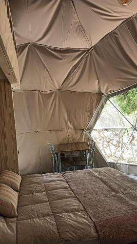 a tent with a bed and a table in it at Glamp Refugio Silvestre 7 Tazas in Molina