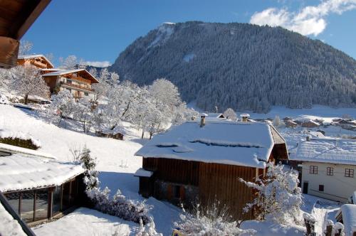 a village covered in snow with a mountain in the background at Hôtel Les Côtes, Résidence Loisirs et Chalets in Morzine