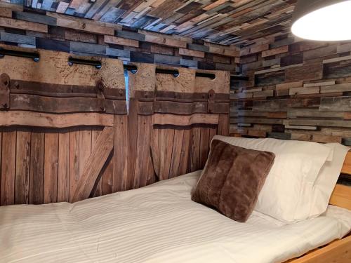 a bed in a room with a wooden wall at The Maisonette - Central Windermere, with parking in Windermere