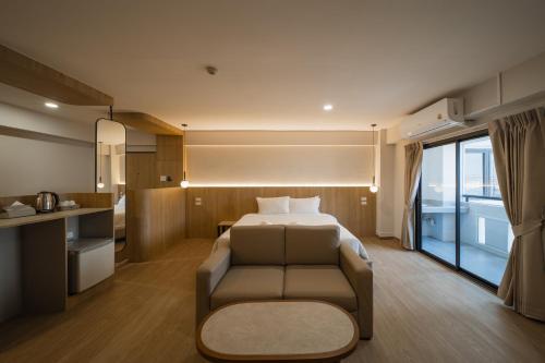 Habitación de hotel con cama, sofá y cocina en Mintara Hotel - โรงแรมมินธารา มีนบุรี, en Min Buri