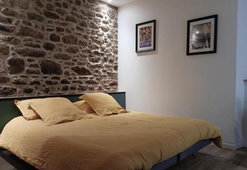 Bett in einem Zimmer mit einer Steinmauer in der Unterkunft La parenthese in Beaussais sur Mer