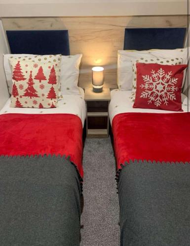 two beds in a room with red and white pillows at Larch View in Tattershall