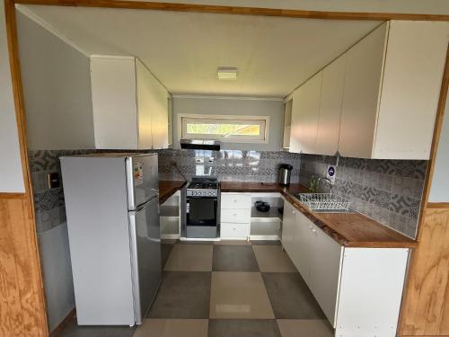 a small kitchen with white cabinets and a refrigerator at Cabañas dunn in Puerto Cisnes