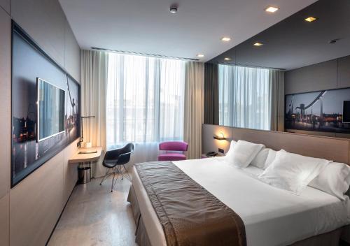 a hotel room with a large bed and a desk at Negresco Princess 4* Sup in Barcelona