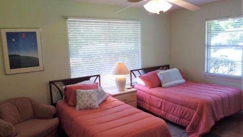 a bedroom with two beds and a chair and a window at Ariel West Duplex in Jekyll Island