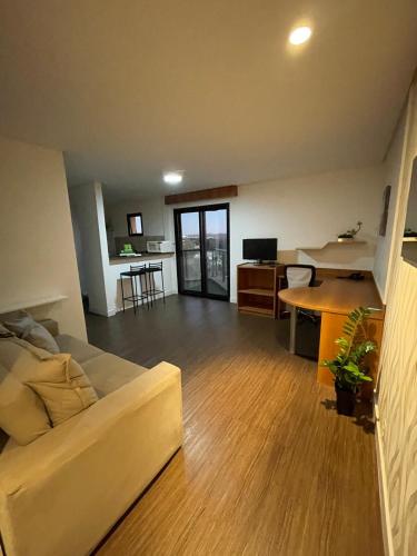 a living room with a couch and a desk and a table at Flat - Excelente localização e vista espetacular in São José dos Campos