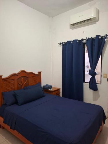 a bedroom with a blue bed and a window at Casa Rubí comfortable and with a private pool in Zihuatanejo