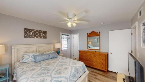 a bedroom with a bed with a ceiling fan and a dresser at Turtle's Nest Duplex in Jekyll Island