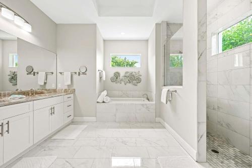 Un baño blanco con ducha y bañera. en Kokomo-Modern Home with Tiki Hut, en Cabo Coral