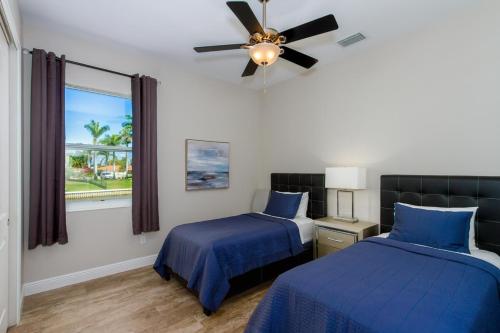 Un dormitorio con dos camas y un ventilador de techo. en Kokomo-Modern Home with Tiki Hut, en Cabo Coral