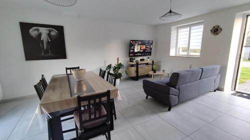 a living room with a dining table and a couch at Maison paisible in Pleucadeuc