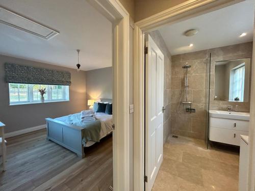 a bedroom with a bed and a bathroom with a shower at The Lodge - Elegant Peaceful Countryside Escape in Bishops Cannings