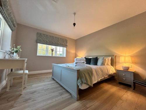 a bedroom with a bed with a dresser and a window at The Lodge - Elegant Peaceful Countryside Escape in Bishops Cannings