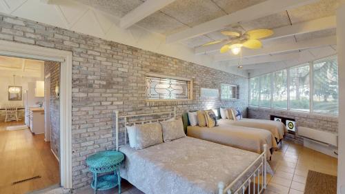 a bedroom with two beds and a brick wall at Meet Me At Sunset in Jekyll Island