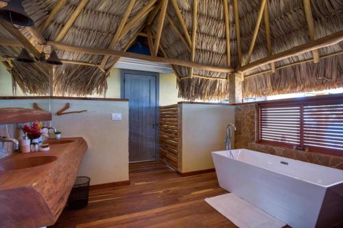 une salle de bain avec une grande baignoire et un lavabo dans l'établissement Kanu Private Island Belize, à Placencia