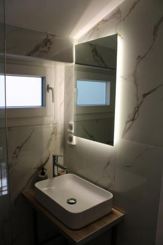 ein weißes Badezimmer mit Waschbecken und Spiegel in der Unterkunft Aenaon Corfu Luxury Apartments #06 - Poseidon Apartment in Ýpsos