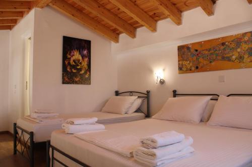 2 Betten in einem Zimmer mit weißen Wänden und Holzdecken in der Unterkunft Aenaon Corfu Luxury Apartments #06 - Poseidon Apartment in Ýpsos