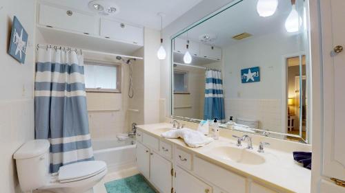 a bathroom with a sink and a toilet and a mirror at Meet Me At Sunset in Jekyll Island