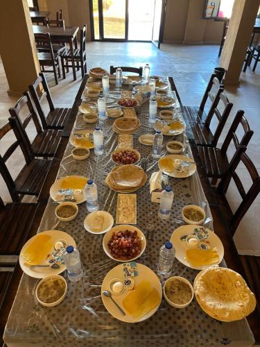 uma longa mesa cheia de pratos e tigelas de comida em Wazidi Resort em Oásis de Siuá