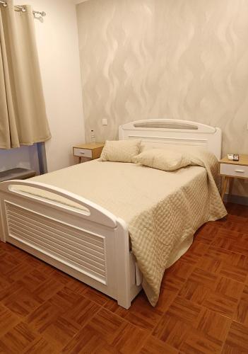 a white bed in a room with wooden floors at Guest House Morais in Sintra