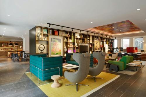 une bibliothèque avec des chaises et des étagères de livres dans l'établissement citizenM Amstel Amsterdam, à Amsterdam