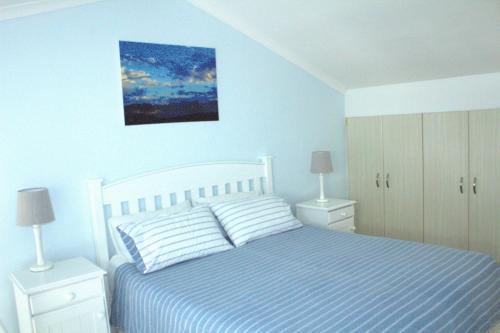 a white bedroom with a bed and two night stands at South Peninsula Coastal Apartment in Cape Town