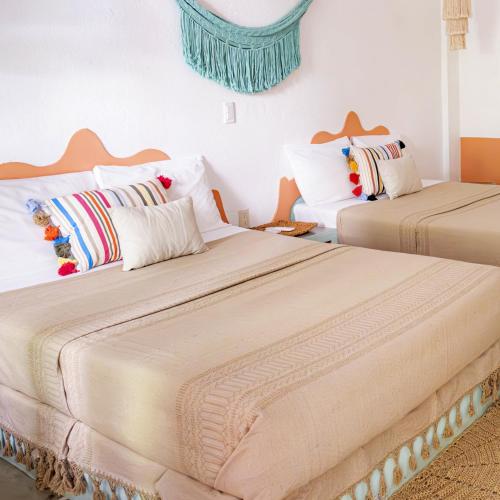 two beds sitting next to each other in a room at Hotel Flor de Maria - Adults Only in Puerto Escondido