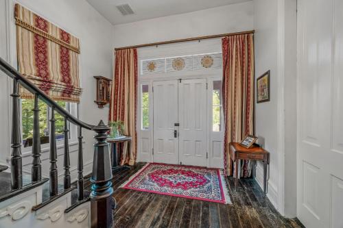 a hallway with a white door and a rug at The Manor - Historic Mansion, Wifi, Covered Porch, Screen Porch, King Bed, Walk to Spas, Shops & Restaurants in Berkeley Springs
