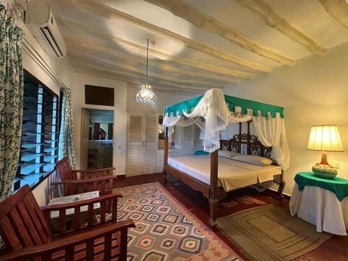a bedroom with a bed with a canopy at Villa Elizabeth by the Golf Club in Malindi