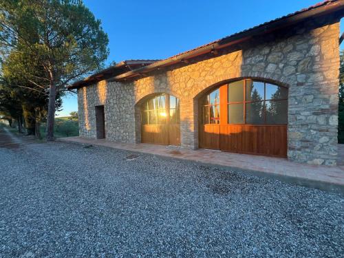 a stone house with large windows and a driveway at LA COLLINA DEI SAPORI Montepulciano in Montepulciano