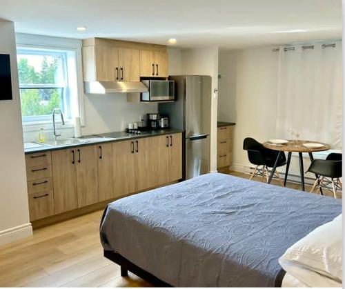 a bedroom with a bed and a kitchen with a table at Hôtel Ardouin in Nominingue