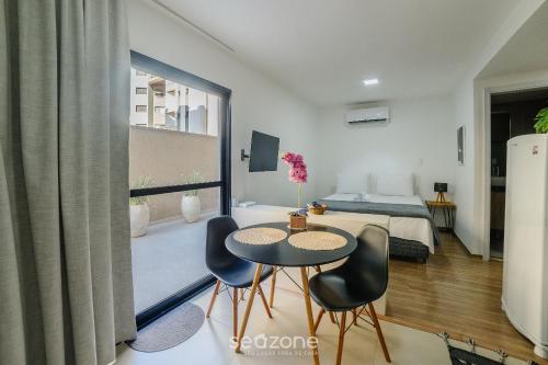 um quarto com uma mesa, cadeiras e uma cama em Sua estadia completa com piscina e academia em Poços de Caldas - NGO em Poços de Caldas