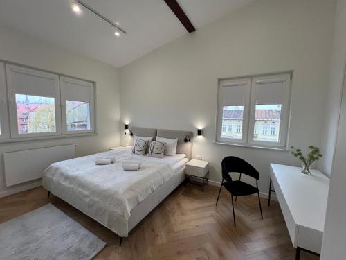 ein weißes Schlafzimmer mit einem großen Bett und einem Stuhl in der Unterkunft Goldhammer Premium Apartments in Tarnów