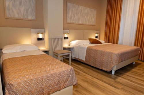 une chambre d'hôtel avec deux lits et un bureau dans l'établissement Lepanto Central, à Messina