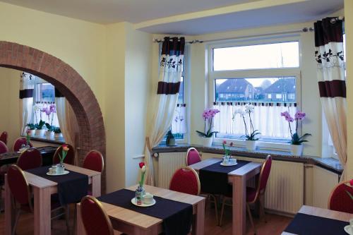 ein Restaurant mit Tischen und Stühlen und einem Fenster in der Unterkunft Pension Nordsee in Norddeich