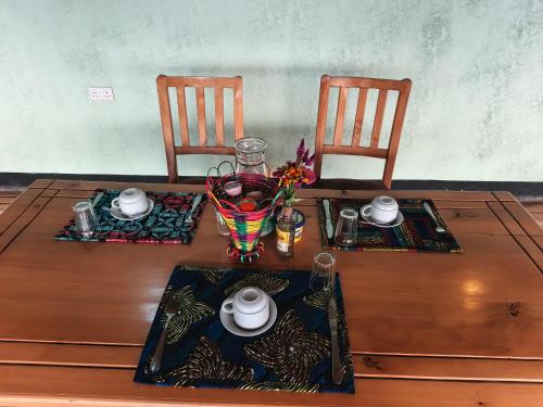 einem Holztisch mit zwei Stühlen und einem Tisch am Tisch am Tisch am Tisch am Tisch am Tisch am Tisch am Tisch am Tisch am Tisch am Tisch am Tisch am Tisch am Tisch in der Unterkunft Nzoghu Heritage Safari Camp in Kasese