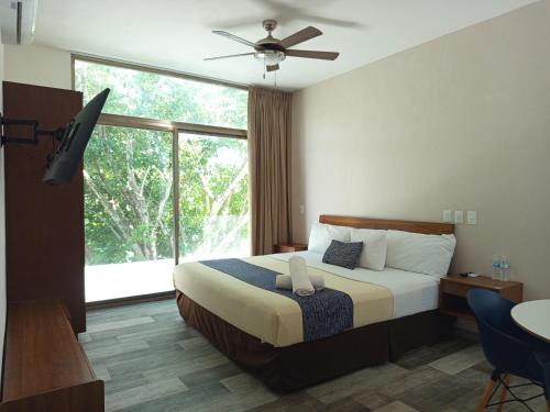 ein Schlafzimmer mit einem Bett und einem großen Fenster in der Unterkunft Hotel Piedra del Caribe Puerto Morelos in Puerto Morelos