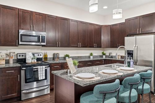 Luxury 3BR Rooftop Apartment Walk to MET and Metro في فيلادلفيا: مطبخ مع دواليب خشبية وجزيرة مطبخ مع كراسي