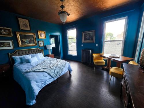 een blauwe slaapkamer met een bed en een tafel en stoelen bij The Lincoln House Inn in Bowling Green