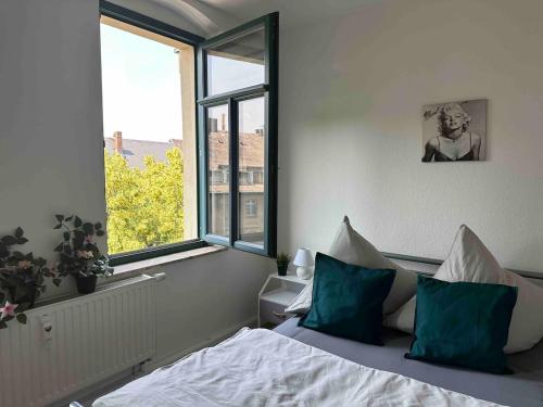 ein Schlafzimmer mit einem Bett mit grünen Kissen und einem Fenster in der Unterkunft 1,5 Zimmer für 4 Personen auf 38qm Wohnfläche in Niederdorla