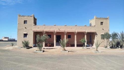ein großes Gebäude mit Bäumen davor in der Unterkunft Gite Omar merzouga in Merzouga