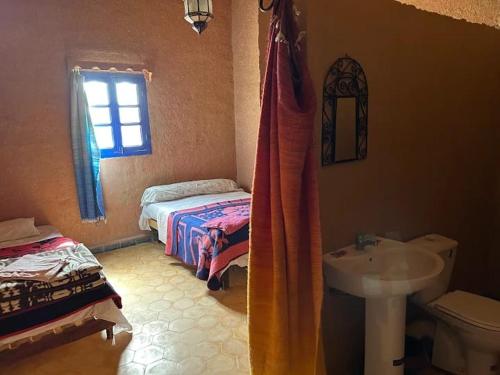 ein Badezimmer mit Waschbecken und Toilette und ein Bett in der Unterkunft Gite Omar merzouga in Merzouga