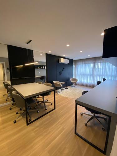 an office with tables and chairs in a room at Loft com Piscina no Rooftop centro de Blumenau in Blumenau
