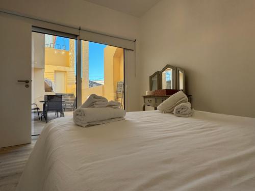 een slaapkamer met een groot wit bed met handdoeken erop bij Charming Seaside Flat in Paul do Mar