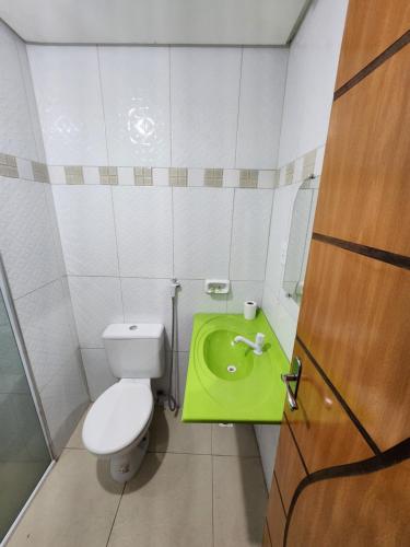 a bathroom with a toilet and a green sink at Eds pousada in Juazeiro do Norte