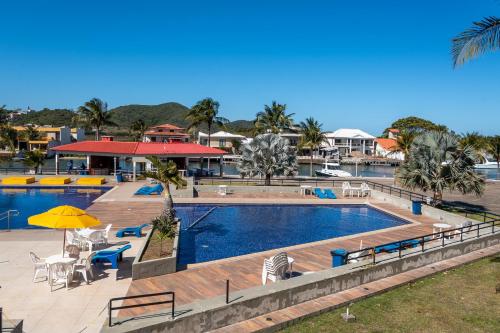 a swimming pool with tables and chairs next to a resort at Apartamento Resort Cabo Frio - Rua dos Biquinis in Cabo Frio