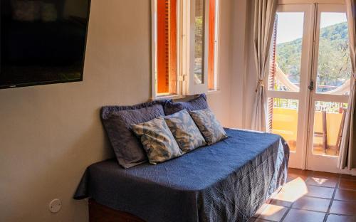 a bedroom with a bed with blue sheets and a window at Apartamento Resort Cabo Frio - Rua dos Biquinis in Cabo Frio