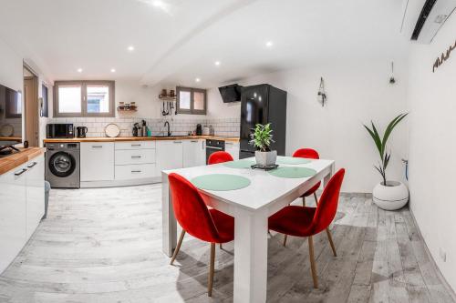 une cuisine avec une table blanche et des chaises rouges dans l'établissement Darja, à Carcassonne