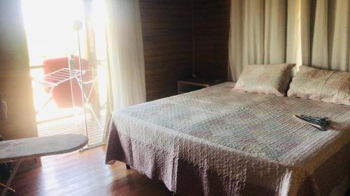 a bedroom with a large bed with a window and a table at Casa com piscina a 300m praia in Imbituba